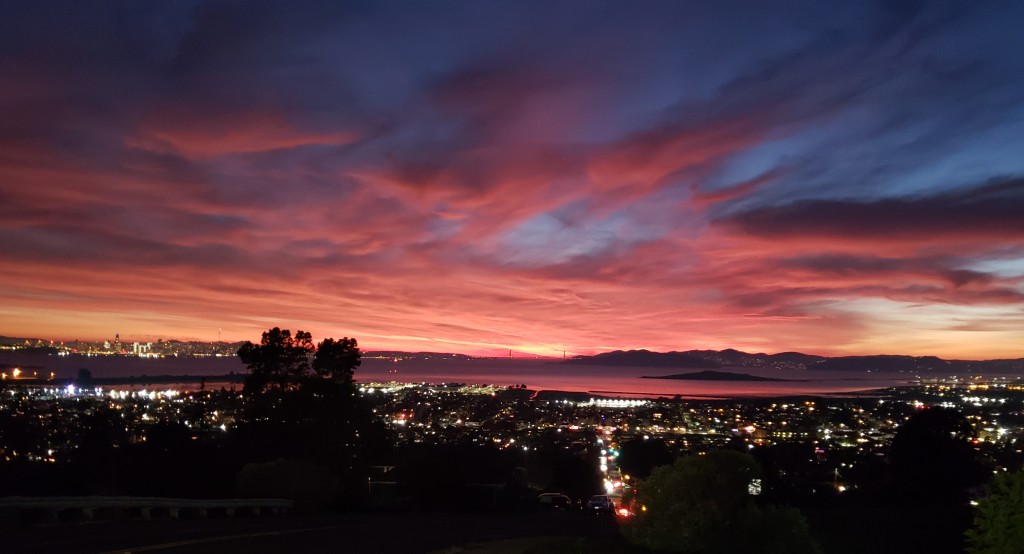 Sunset over the bay with views of San Francisco and the Golden Gate bridge and El Cerrito city lights